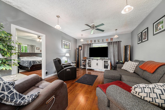 living area with ceiling fan, a textured ceiling, and hardwood / wood-style floors