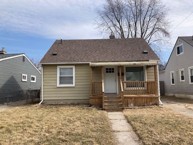 bungalow-style house featuring covered porch, roof with shingles, and a front lawn