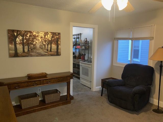 sitting room with carpet floors, ceiling fan, and baseboards