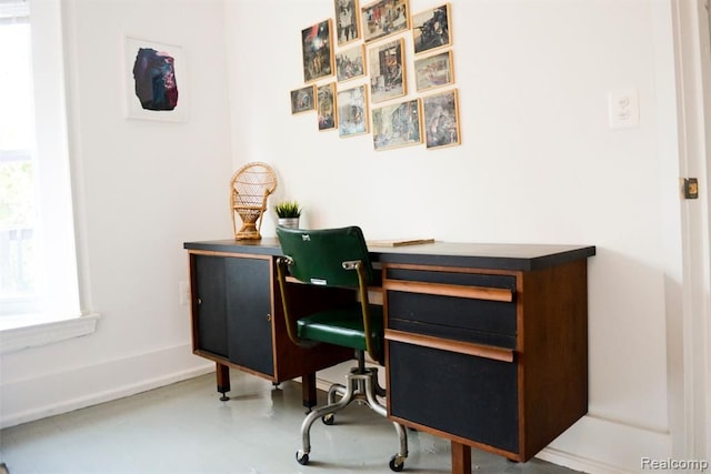 office area featuring concrete floors and baseboards