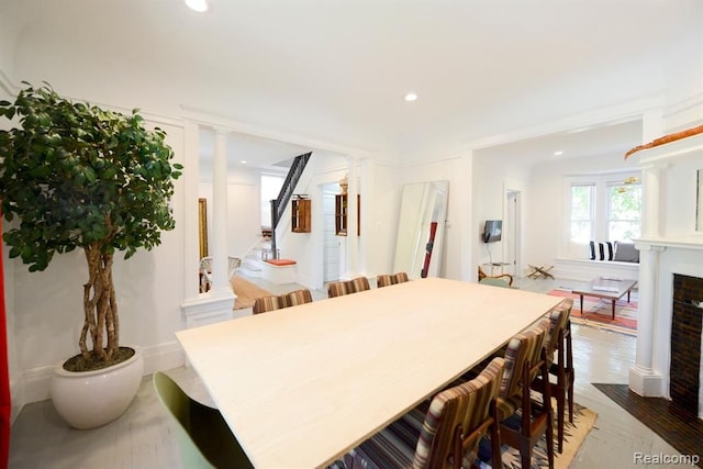 kitchen featuring wood finished floors, a fireplace with flush hearth, decorative columns, and recessed lighting