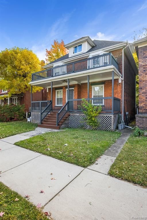 view of front of house with a porch, a front yard, brick siding, and a balcony