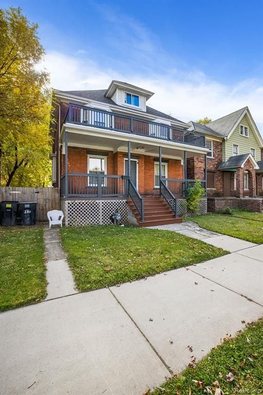 view of front of home featuring a porch, brick siding, a balcony, and a front lawn