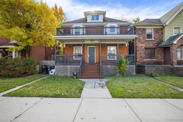 view of front facade with a porch, a front lawn, a balcony, and brick siding