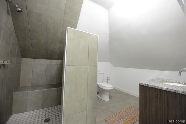 bathroom featuring baseboards, tiled shower, toilet, lofted ceiling, and tile patterned flooring