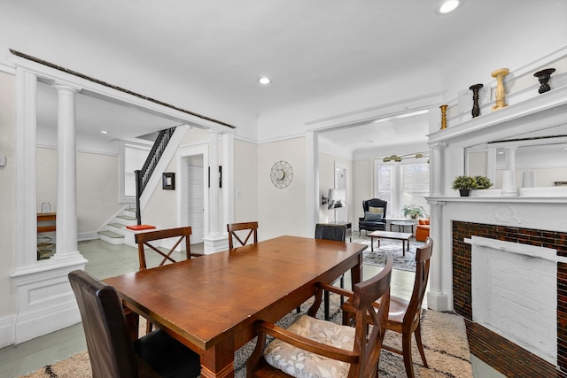 dining area with a fireplace with flush hearth, stairway, wood finished floors, ornate columns, and recessed lighting