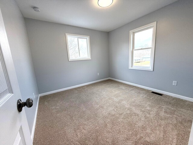 unfurnished room with carpet, plenty of natural light, and visible vents