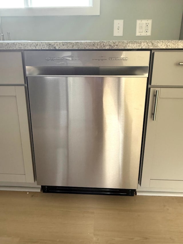 details featuring light wood finished floors and stainless steel dishwasher