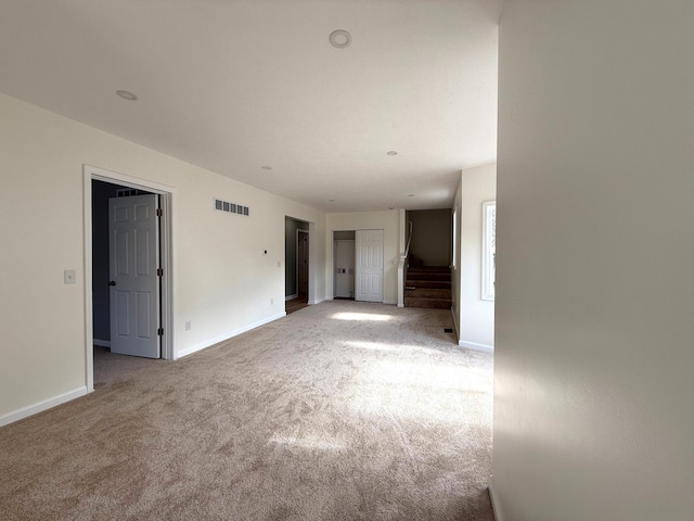 empty room with stairs, carpet flooring, visible vents, and baseboards