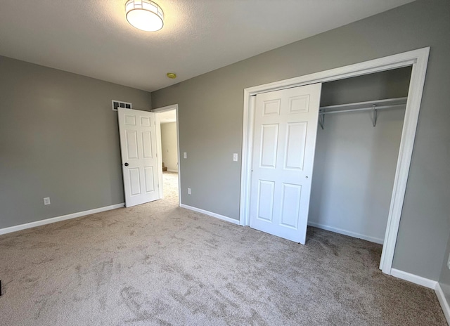 unfurnished bedroom with carpet floors, a closet, visible vents, and baseboards