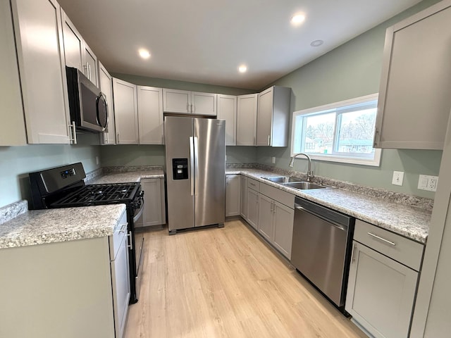 kitchen featuring recessed lighting, light countertops, appliances with stainless steel finishes, a sink, and light wood-type flooring