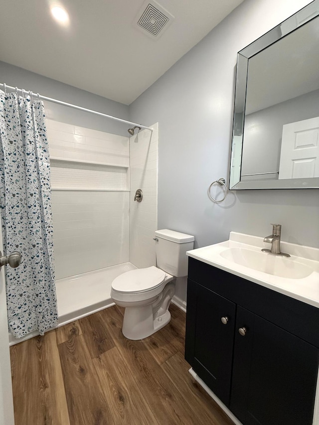 bathroom with toilet, visible vents, wood finished floors, and tiled shower