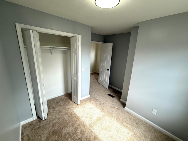 unfurnished bedroom featuring baseboards, a closet, and carpet flooring