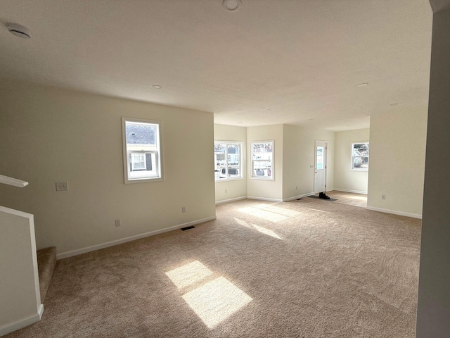 unfurnished living room with carpet floors, visible vents, stairway, and baseboards