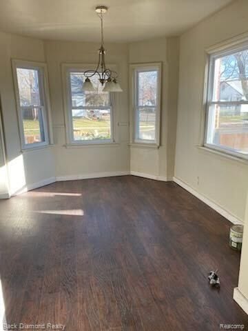 unfurnished dining area featuring dark wood-style flooring and baseboards