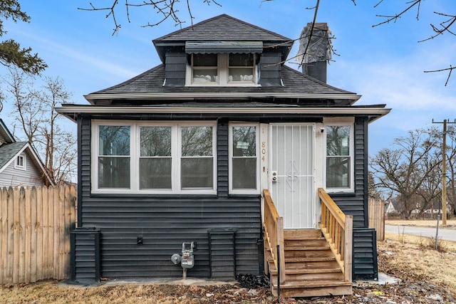 bungalow featuring entry steps, a chimney, and fence