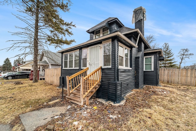 view of front of property with entry steps, fence, and a chimney