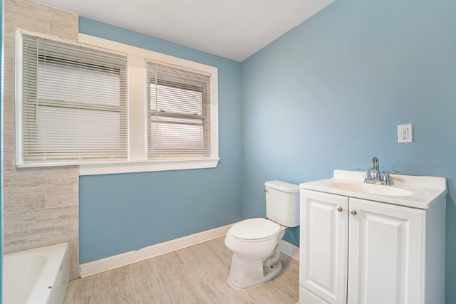 full bathroom with a bathing tub, toilet, wood finished floors, vanity, and baseboards