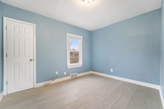 unfurnished room with baseboards, visible vents, and wood finished floors