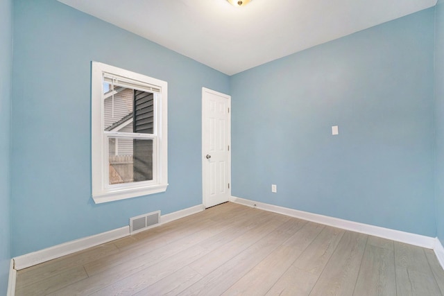 empty room featuring baseboards, visible vents, and wood finished floors