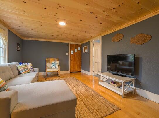 living area with wooden ceiling, baseboards, and wood finished floors