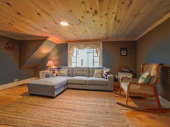 sitting room with vaulted ceiling, wooden ceiling, wood finished floors, and baseboards