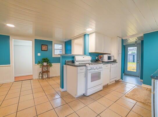 kitchen featuring dark countertops, white appliances, white cabinetry, and light tile patterned flooring