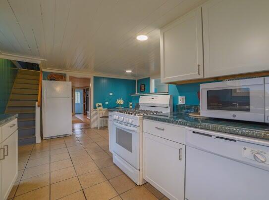 kitchen with light tile patterned floors, wooden ceiling, white appliances, white cabinets, and dark countertops