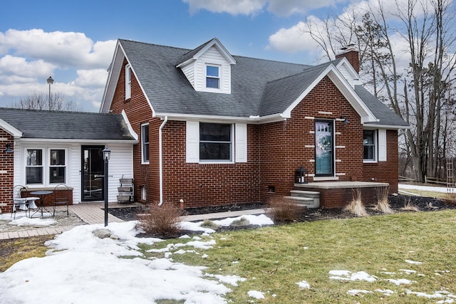 view of front of house featuring a patio area, a shingled roof, a lawn, and brick siding