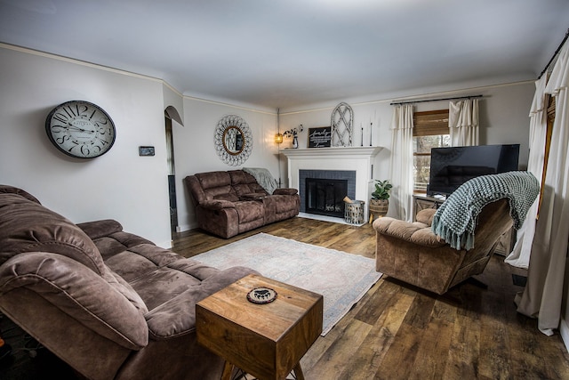 living area featuring a brick fireplace, ornamental molding, and wood finished floors