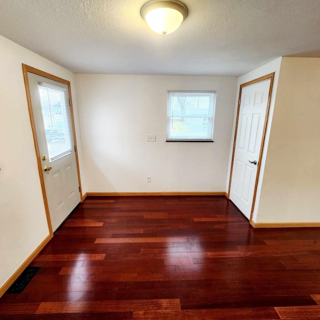 unfurnished room featuring visible vents, a textured ceiling, baseboards, and hardwood / wood-style flooring