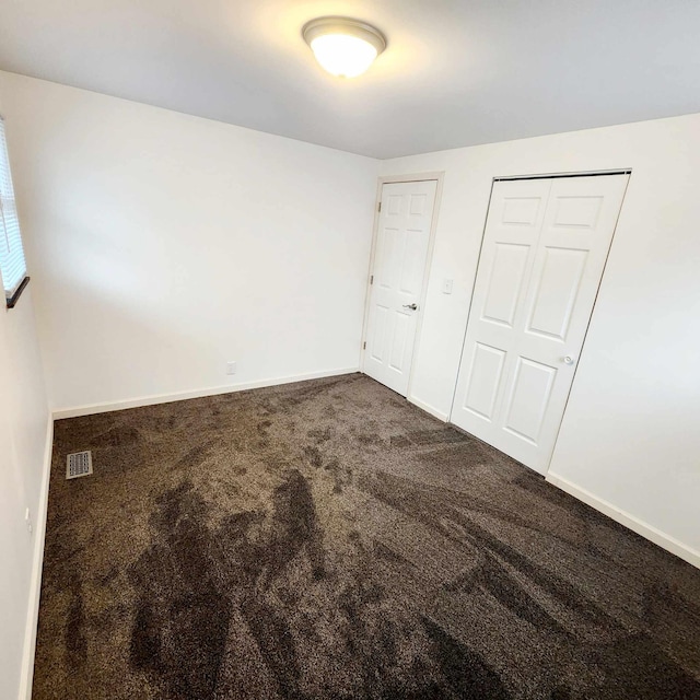 unfurnished bedroom with a closet, carpet, visible vents, and baseboards