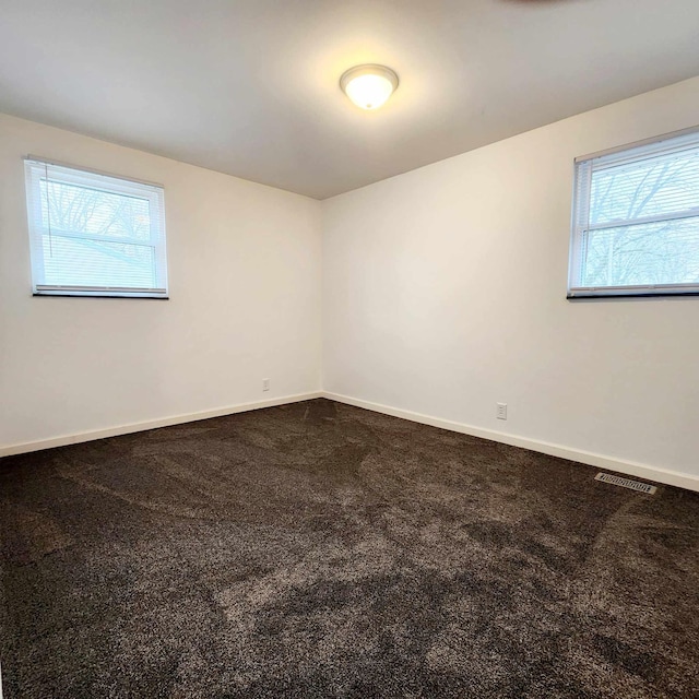 spare room with carpet floors, plenty of natural light, visible vents, and baseboards