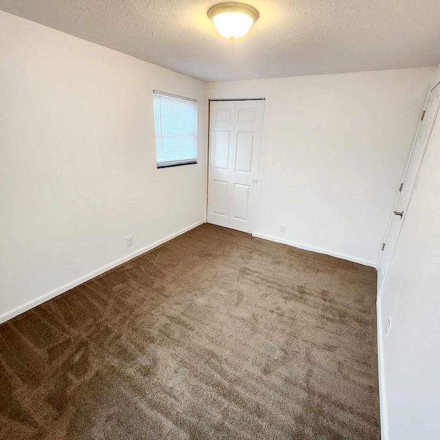 unfurnished bedroom with carpet, baseboards, and a textured ceiling