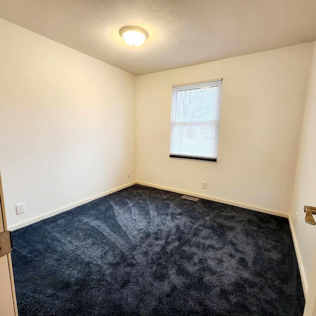 unfurnished room with a textured ceiling, carpet flooring, and baseboards