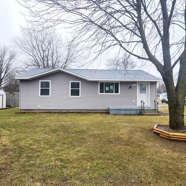 rear view of house featuring a shed, roof with shingles, a lawn, and an outdoor structure