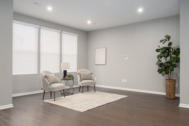 living area with a healthy amount of sunlight, baseboards, visible vents, and dark wood finished floors