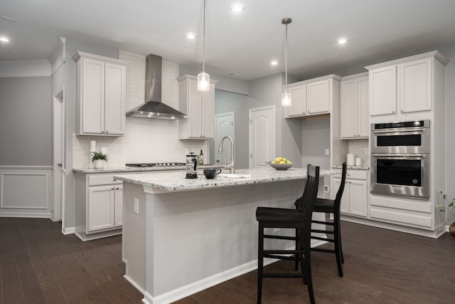 kitchen featuring double oven, white cabinets, wall chimney exhaust hood, and dark wood-style floors