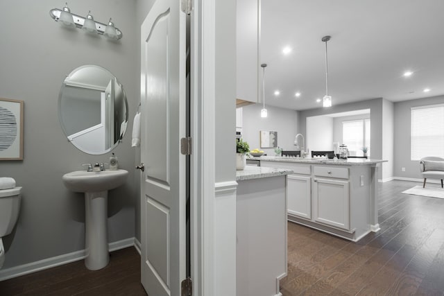 bathroom featuring a sink, baseboards, wood finished floors, and recessed lighting