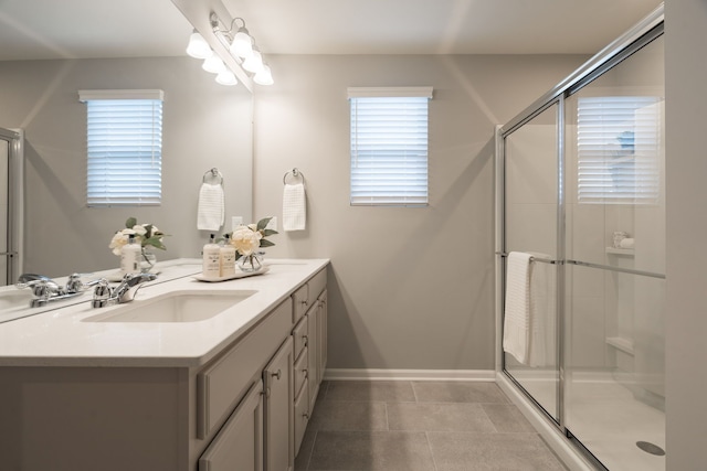 bathroom with a stall shower, tile patterned flooring, vanity, and baseboards