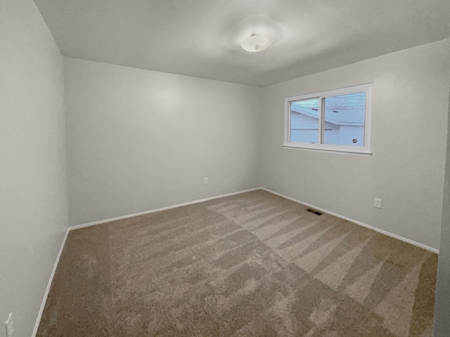 carpeted empty room featuring visible vents and baseboards