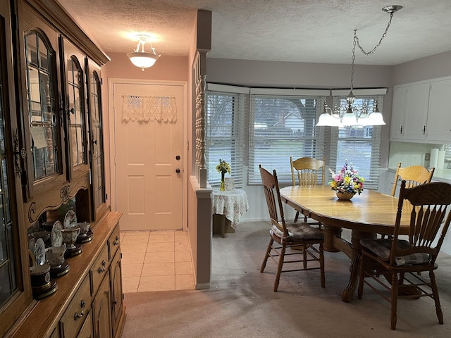 dining area featuring a textured ceiling, light tile patterned floors, and light carpet