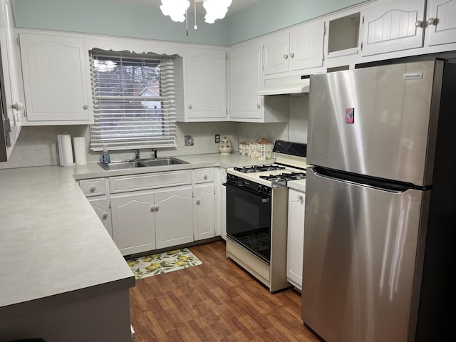 kitchen with gas range, freestanding refrigerator, light countertops, under cabinet range hood, and a sink