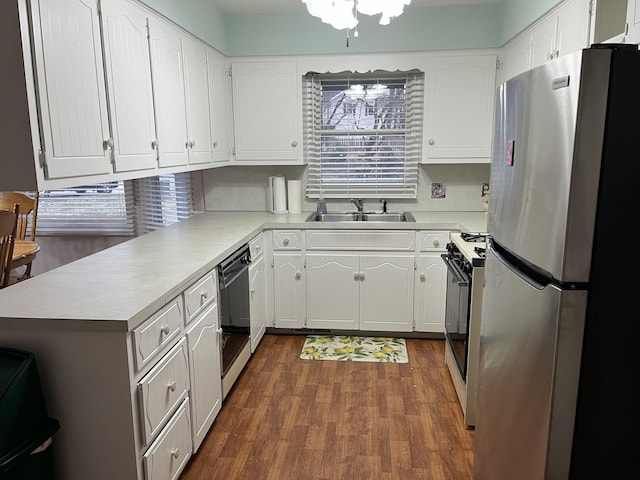 kitchen with dishwasher, freestanding refrigerator, gas range oven, white cabinetry, and a sink