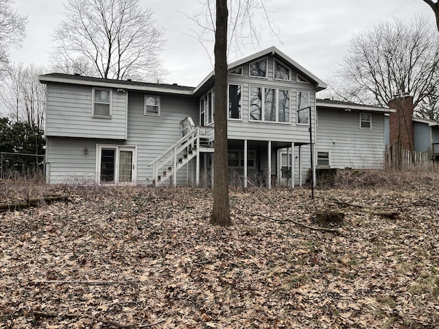 back of property featuring stairs, fence, and a sunroom