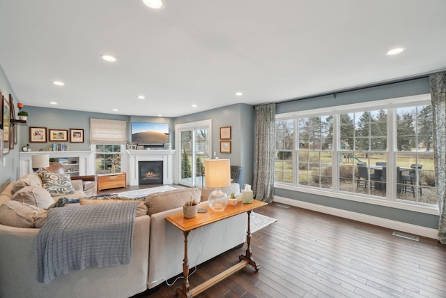 living room with a glass covered fireplace, dark wood-style flooring, baseboards, and recessed lighting