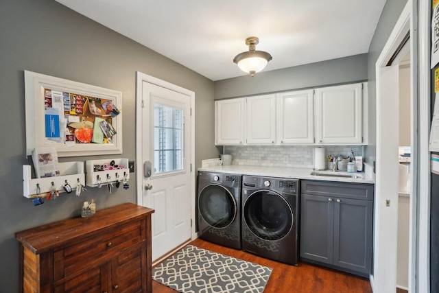 washroom with washing machine and dryer, dark wood-type flooring, a sink, and cabinet space