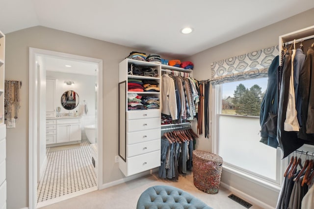 walk in closet featuring vaulted ceiling, light carpet, and visible vents