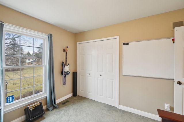 carpeted bedroom featuring a closet, visible vents, and multiple windows