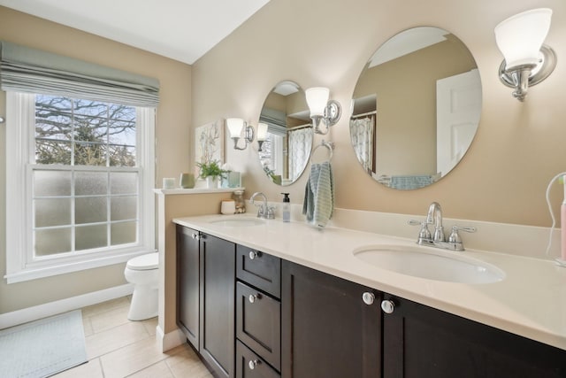 full bathroom featuring double vanity, toilet, a sink, and tile patterned floors